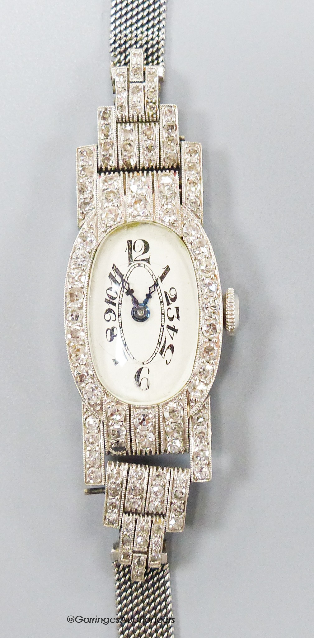 A lady's mid 20th century white metal (stamped platinum) and diamond set cocktail watch, with tumbling numerals, on an 18ct mesh link strap